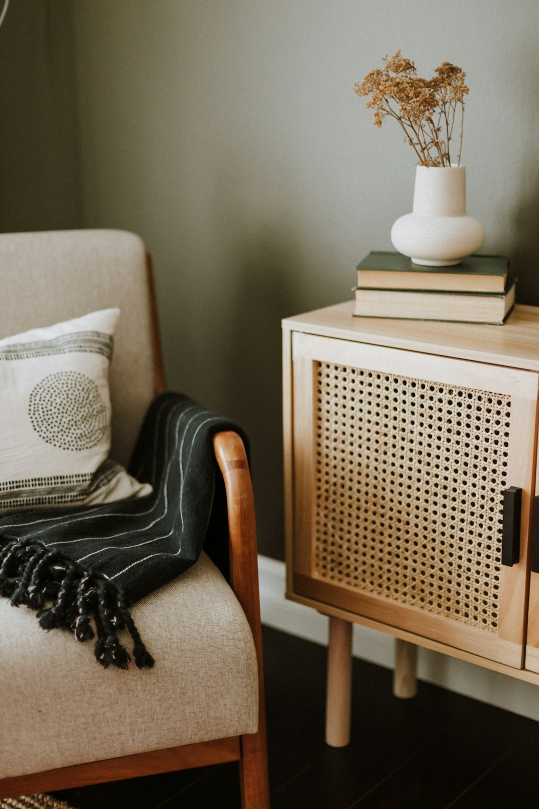 a-chair-with-a-blanket-on-it-next-to-a-table-with-a-vase-on-it-vpvn23hs9vg