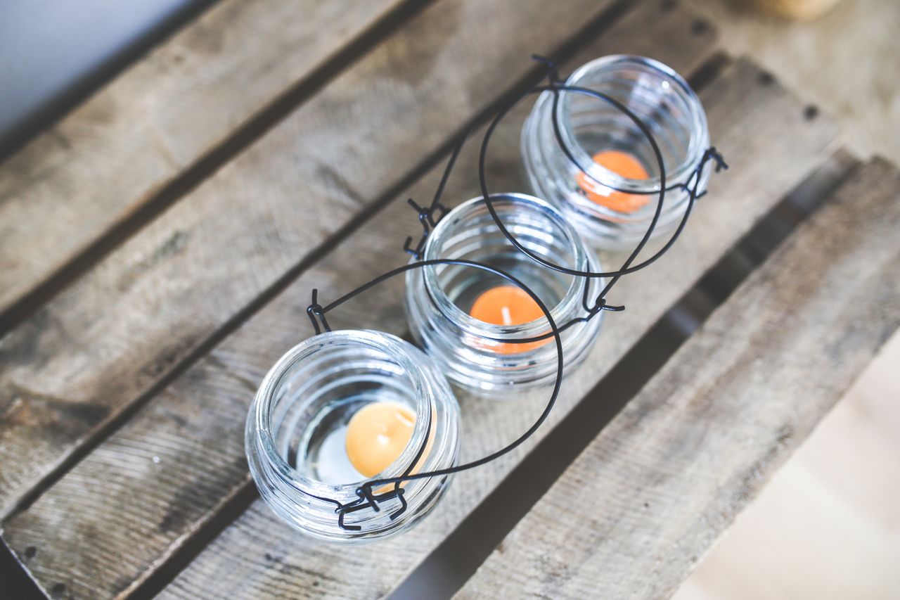 Top view of glass candleholders with orange tealights on a wooden surface.